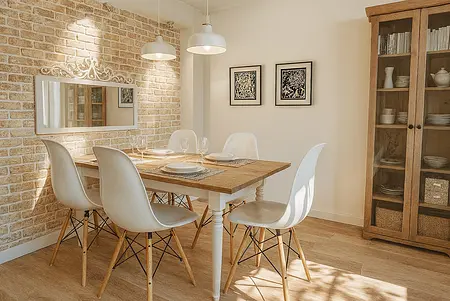 Jadalnia z białymi krzesłami, drewnianym stołem i ceglaną ścianą w stylu boho, minimalistycznym i skandynawskim.