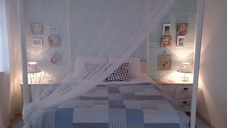 Sypialnia w stylu boho z jasnymi ścianami, łóżkiem i lampkami.