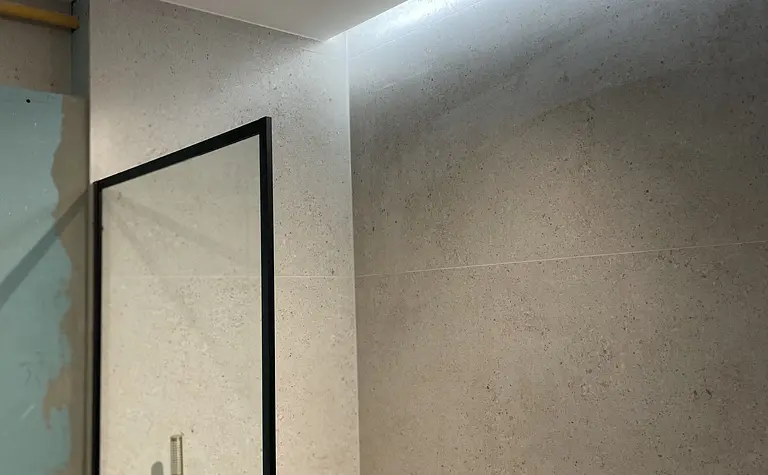 Wnętrze łazienki z szarymi ścianami, czarnym oświetleniem i prysznicem w stylu glamour i nowoczesnym