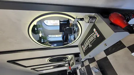 Wnętrze barber shopu z lustrami, roślinami i nowoczesnym wyposażeniem.
