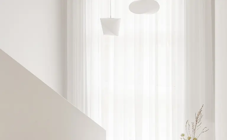 Przedpokój w stylu japandi z białymi zasłonami i minimalistycznymi lampami.