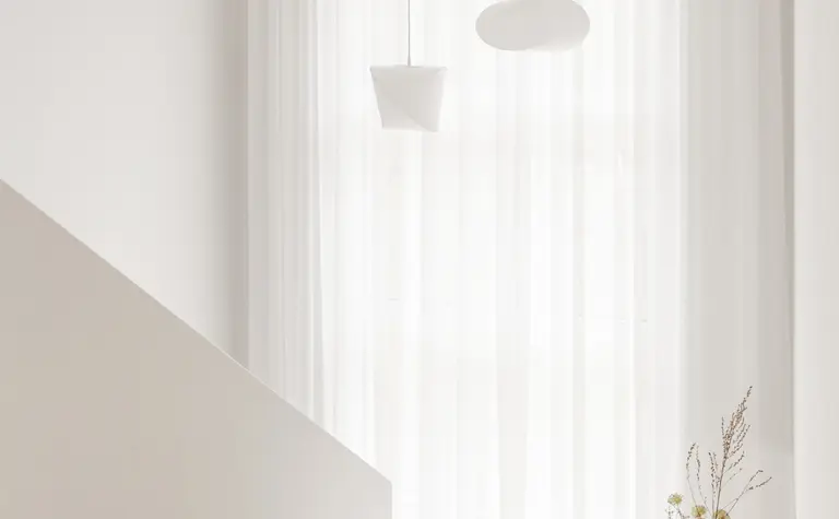 Przedpokój w stylu japandi z białymi zasłonami i minimalistycznymi lampami.