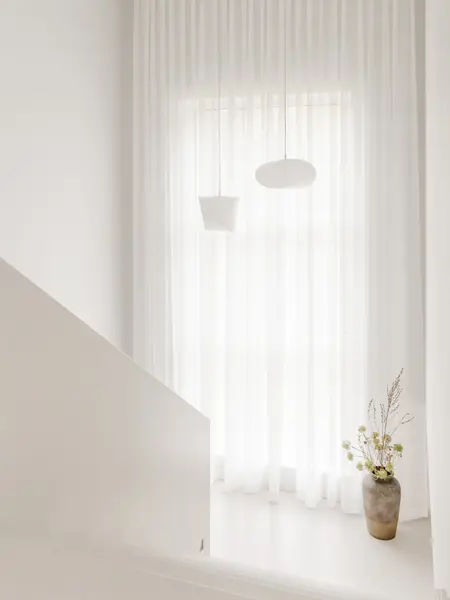 Przedpokój w stylu japandi z białymi zasłonami i minimalistycznymi lampami.