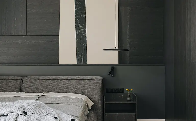 Wnętrze sypialni z szarym łóżkiem i nowoczesnym oświetleniem w stylu industrialnym i minimalistycznym.
