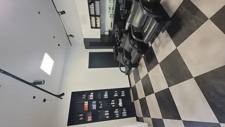 Wnętrze salonu fryzjerskiego z czarnymi fotelami i białymi meblami, styl industrialny i nowoczesny.