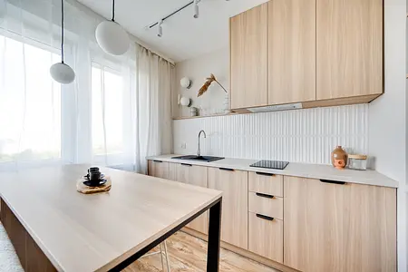 Wnętrze kuchni w stylu japandi z drewnianymi meblami i białymi detalami.