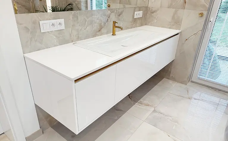 Nowoczesna łazienka z białą umywalką i złotymi detalami w stylu glamour.