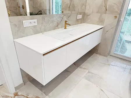 Nowoczesna łazienka z białą umywalką i złotymi detalami w stylu glamour.