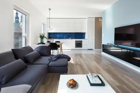 Wnętrze salonu z minimalistycznym designem, białą kuchnią i niebieskim tłem.