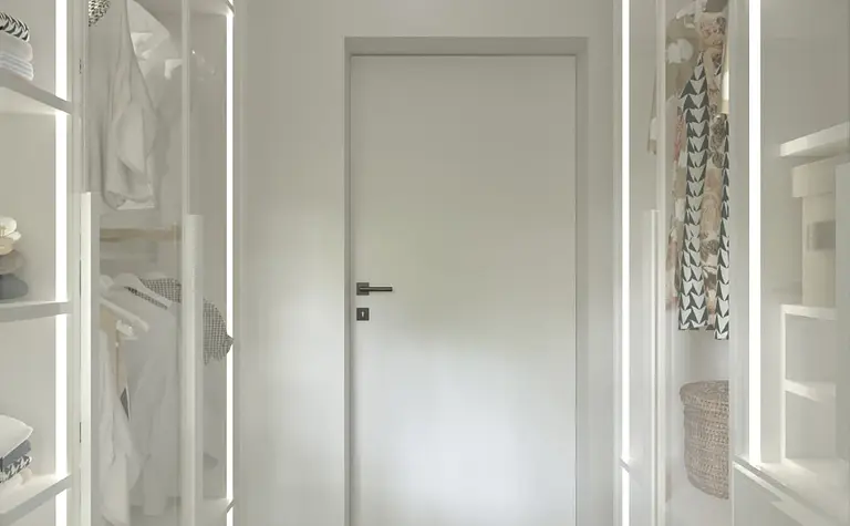 Garderoba minimalistyczna z białymi meblami i jasnym dywanem, idealna do przechowywania.