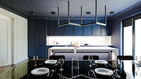 Kuchnia w stylu art deco i współczesnym z granatowymi meblami i białym blatem.