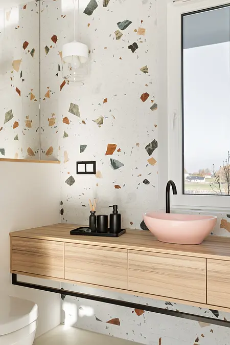 Nowoczesna łazienka z elementami art deco, boho i glamour, z drewnianą szafką i różową umywalką.