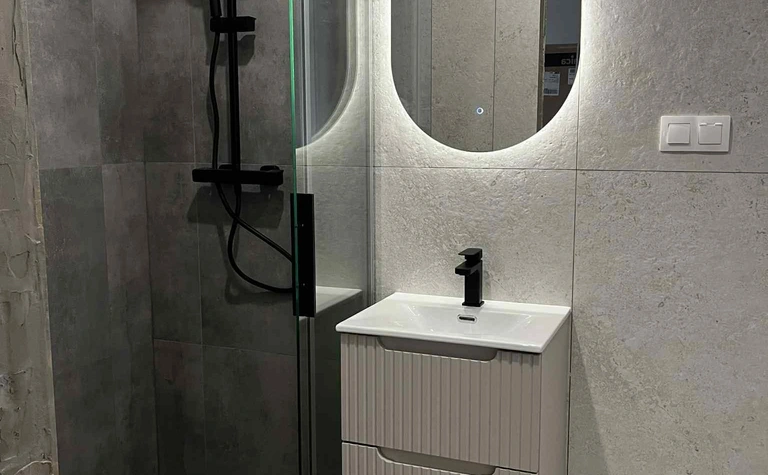 Nowoczesna łazienka z kabiną prysznicową i minimalistycznym umywalką w stylu glamour.