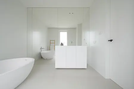 Nowoczesna łazienka z minimalistycznym designem, biała wanna, lustro i szare ściany.