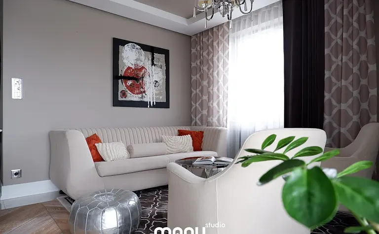 Nowoczesny salon z jasną sofą, czerwonymi poduszkami i dekoracyjnym obrazem. Styl tradycyjny.