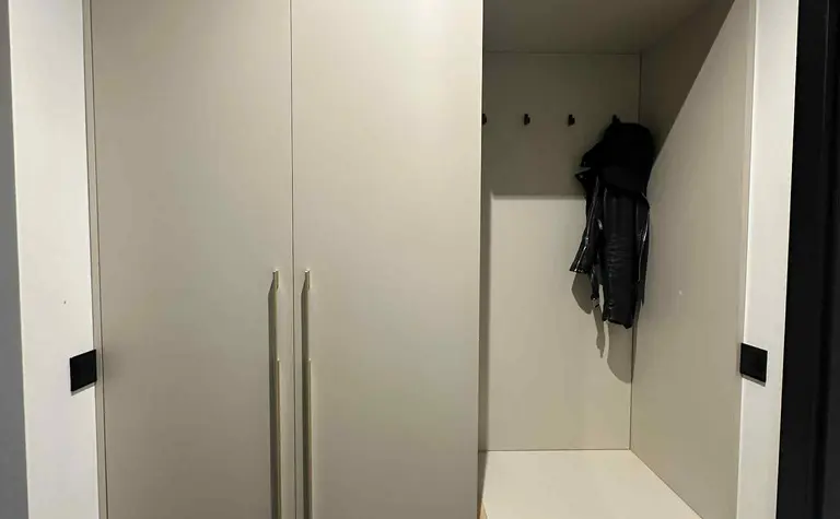 Garderoba w stylu industrialnym i nowoczesnym z beżowymi meblami.