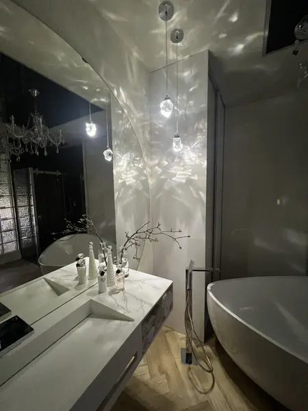 Elegancka łazienka z białą wanną i stylowymi lampami w stylu glamour.