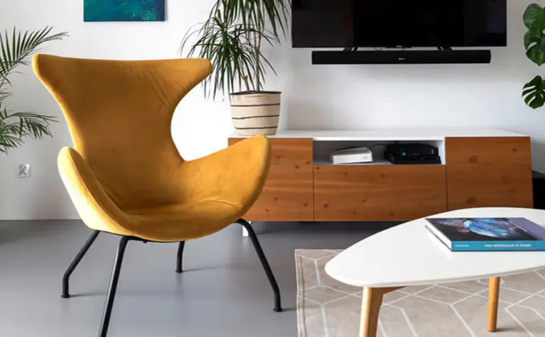 Wnętrze minimalistycznego salonu z żółtym fotelem, telewizorem i roślinami