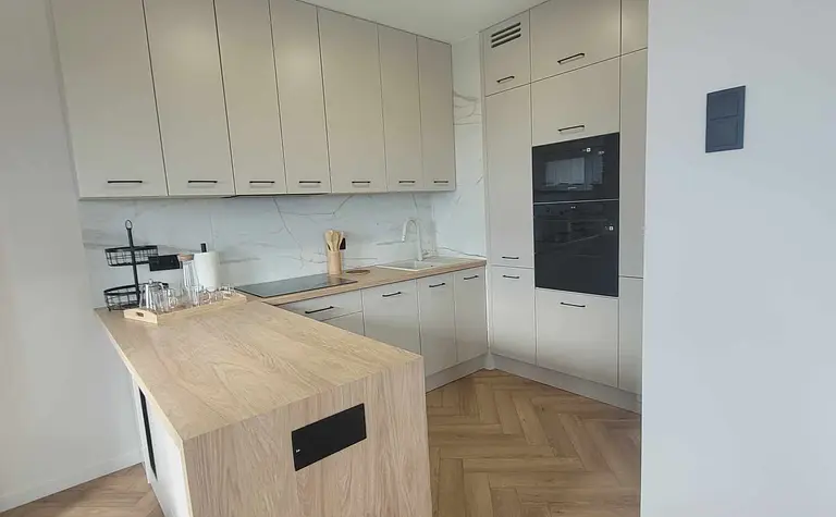Nowoczesna kuchnia z szarymi meblami i drewnianą podłogą, idealna do gotowania.