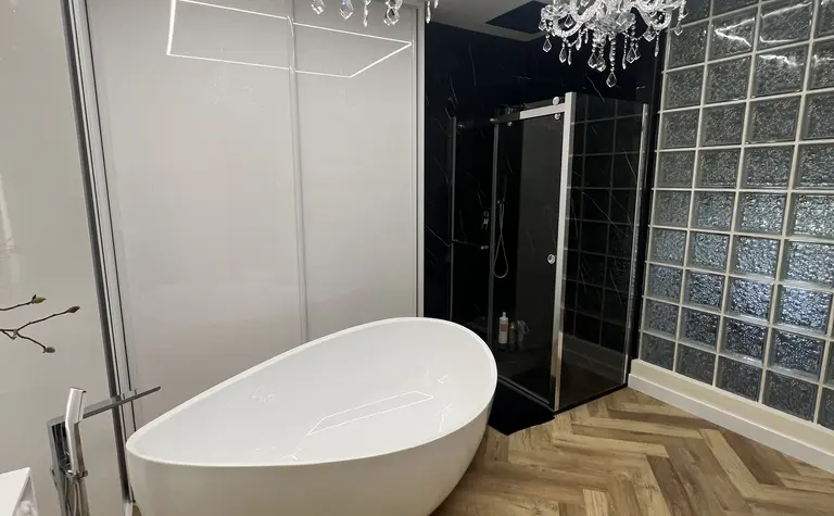 Nowoczesna łazienka z białą wanną, szklanym prysznicem i kryształowymi żyrandolami w stylu glamour.