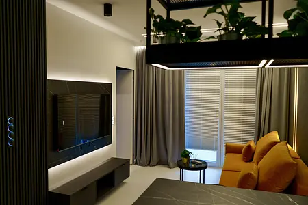 Wnętrze nowoczesnego salonu z szarymi zasłonami, żółtą sofą i stylowym telewizorem.