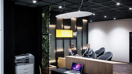 Wnętrze biura z drewnianym biurkiem, roślinami i nowoczesnym wystrojem industrialnym.