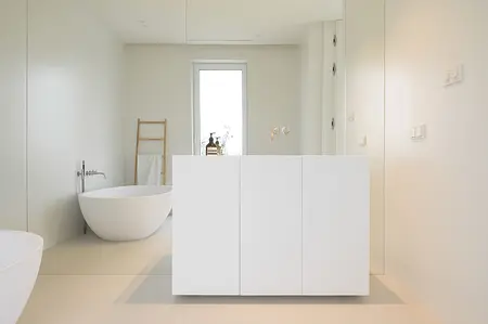 Minimalistyczna łazienka z białą wanną, meblami i drewnianymi detalami.