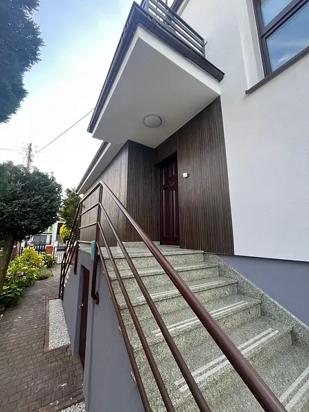 Widok na wejście do budynku z drewnianą elewacją i schodami, styl tradycyjny.