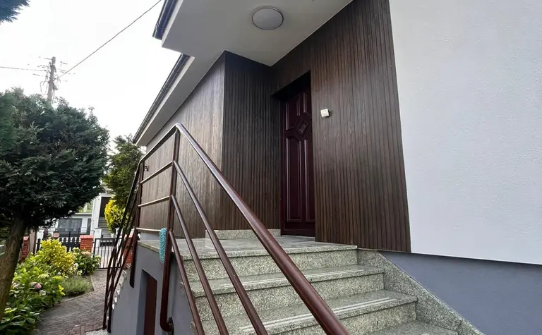 Widok na wejście do budynku z drewnianą elewacją i schodami, styl tradycyjny.