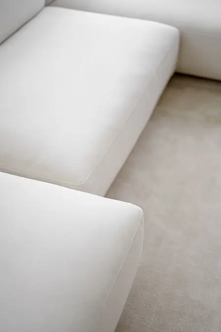 Minimalistyczna kanapa w kolorze białym na jasnym dywanie, styl minimalistyczny i nowoczesny.