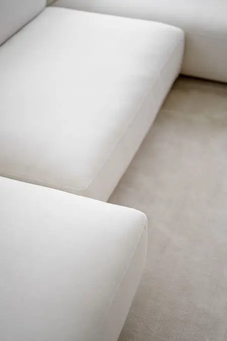 Minimalistyczna kanapa w kolorze białym na jasnym dywanie, styl minimalistyczny i nowoczesny.