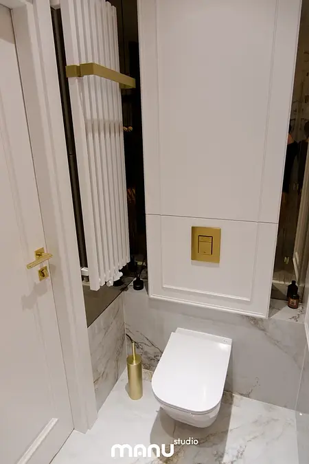 Nowoczesna łazienka z białymi meblami, tradycyjnymi detalami i złotymi akcentami.