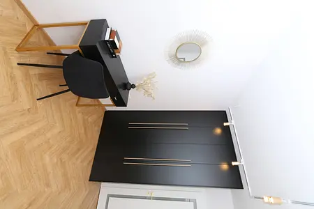 Wnętrze gabinetu z czarnym biurkiem, minimalistycznym stylem i nowoczesnymi akcentami.