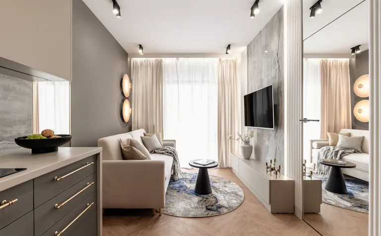 Nowoczesny salon z jasną sofą, drewnianą podłogą i dużymi oknami.