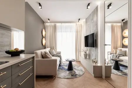 Nowoczesny salon z jasną sofą, drewnianą podłogą i dużymi oknami.