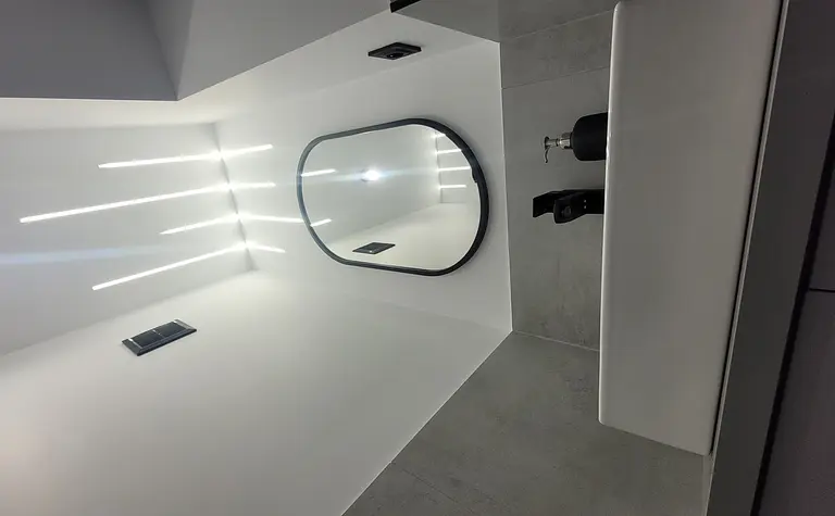Minimalistyczna łazienka z białą umywalką i szarymi akcentami.