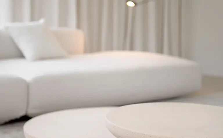 Minimalistyczne wnętrze salonu z białą sofą i okrągłymi stolikami w stylu minimaluxe