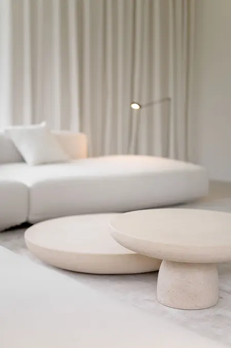 Minimalistyczne wnętrze salonu z białą sofą i okrągłymi stolikami w stylu minimaluxe