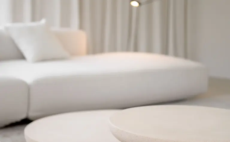 Minimalistyczne wnętrze salonu z białą sofą i okrągłymi stolikami w stylu minimaluxe