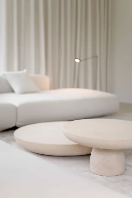 Minimalistyczne wnętrze salonu z białą sofą i okrągłymi stolikami w stylu minimaluxe