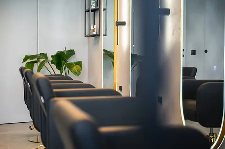 Wnętrze salonu fryzjerskiego z czarnymi fotelami i roślinami, styl industrialny i współczesny