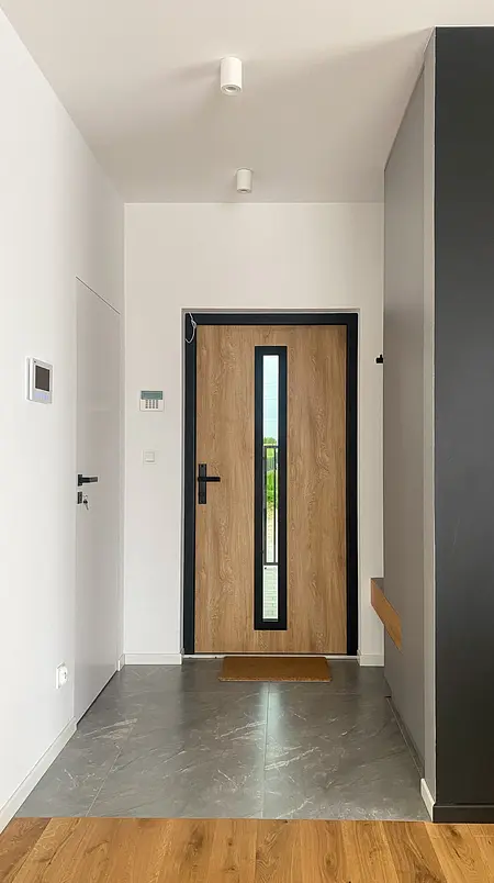 Przedpokój w stylu minimalistycznym z drewnianymi elementami i szarymi płytkami.