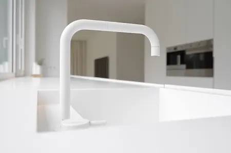 Minimalistyczna kuchnia z białym zlewem i kranem w stylu minimaluxe.
