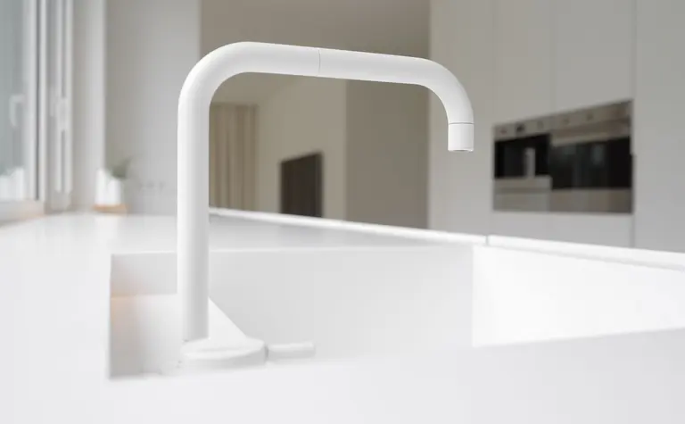 Minimalistyczna kuchnia z białym zlewem i kranem w stylu minimaluxe.