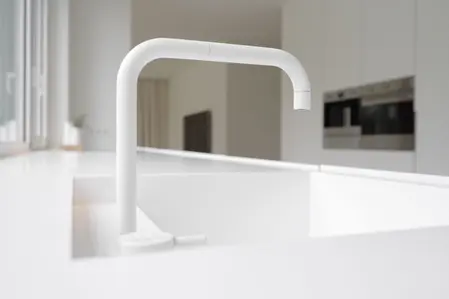 Minimalistyczna kuchnia z białym zlewem i kranem w stylu minimaluxe.
