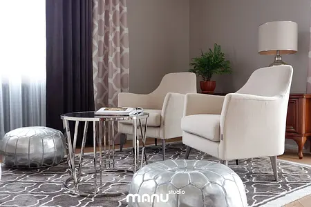 Wnętrze salonu z beżowymi fotelami, szklanym stolikiem i rośliną, styl tradycyjny.