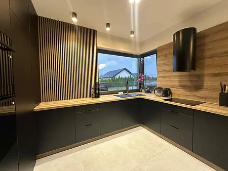 Kuchnia w stylu industrialnym z czarnymi meblami i drewnianymi detalami.