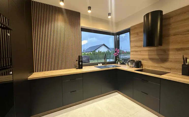 Kuchnia w stylu industrialnym z czarnymi meblami i drewnianymi detalami.