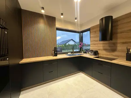 Kuchnia w stylu industrialnym z czarnymi meblami i drewnianymi detalami.