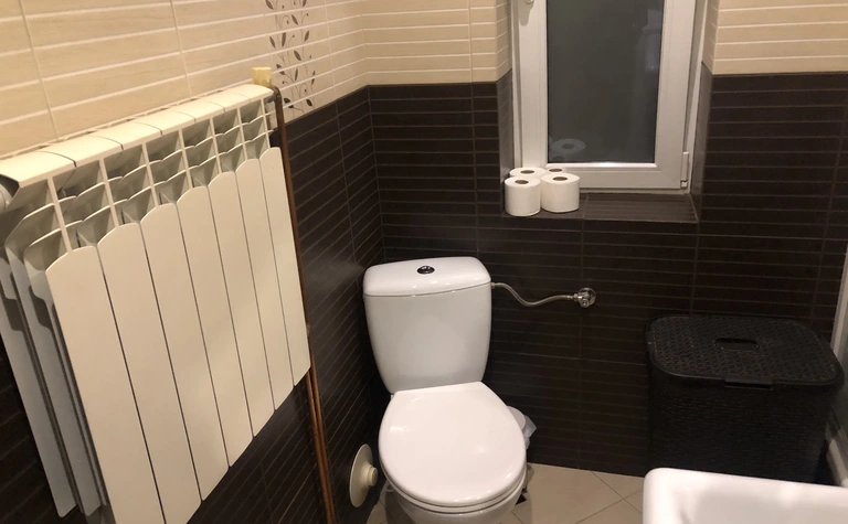 Łazienka z białą toaletą, brązowymi płytkami i minimalistycznym designem.